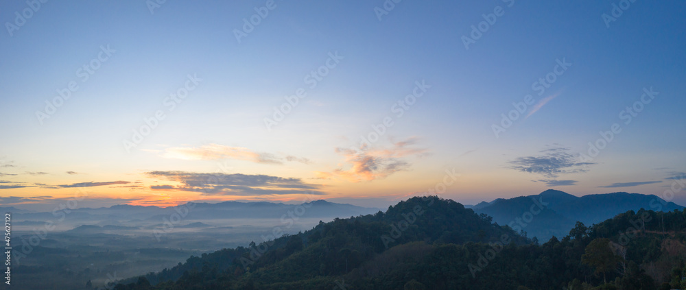 aerial view scenery sunrise above the mountain in tropical rainforest..slow floating fog blowing cover on the mountain look like as a sea of mist. .beautiful sunrise in the mist background. aerial view scenery sunrise above the mountain in tropical rainforest..slow floating fog blowing cover on the mountain look like as a sea of mist. .beautiful sunrise in the mist background.