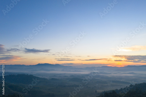 Fototapeta Naklejka Na Ścianę i Meble -  aerial view scenery sunrise above the mountain in tropical rainforest..slow floating fog blowing cover on the mountain look like as a sea of mist. .beautiful sunrise in the mist background.