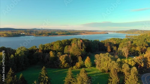 A drone shot of a Hudson river with green trees and a valley on a sunset