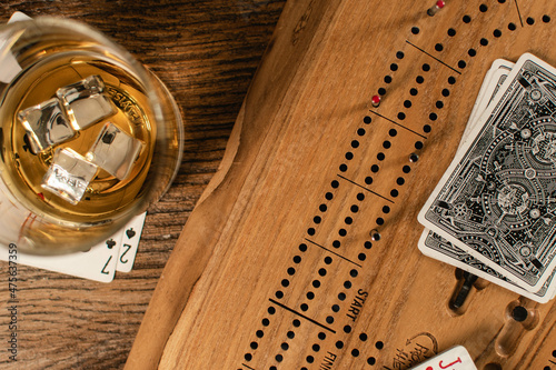 A glass of whisky awaits the card player's hand in a game of cribbage. 