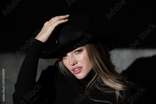 Girl in fashion hat. Sexy alluring woman, sensual young model looking seduce on black studio. Fashion portrait of elegant woman in shadow, glamor light. © Volodymyr