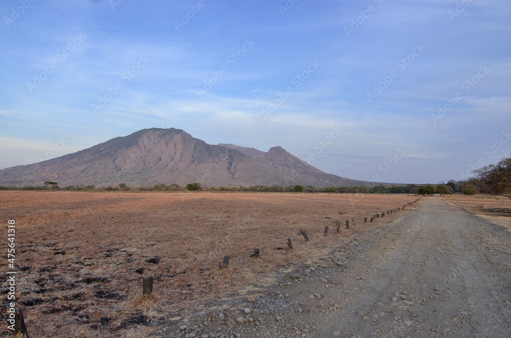 Scenic view of Mount Baluran and dirt road on the foreground. 