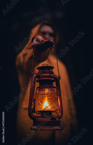 Vertical shot of a young man in a yellow hoodie holding a lantern photo