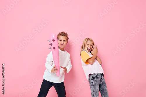 Cheerful boy and girl fun toys pink background