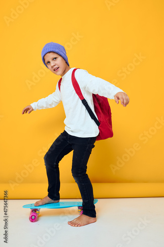 happy schoolboy rides a skateboard in a blue hat isolated background