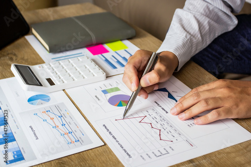 Young businessman pointing to last quarter's earnings and planning revision of business finances next quarter, businessman pointing to past company volatility, businessman planning ideas.