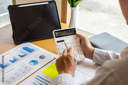 Young businessman presses last quarter earnings calculator to find solution of next quarter business finance, business people calculate numbers for workplace meeting, business people planning concept.