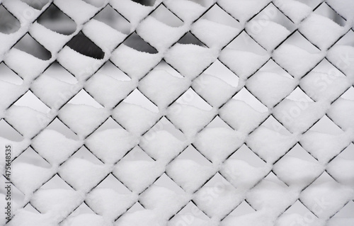 Lattice steel fence during snowfall