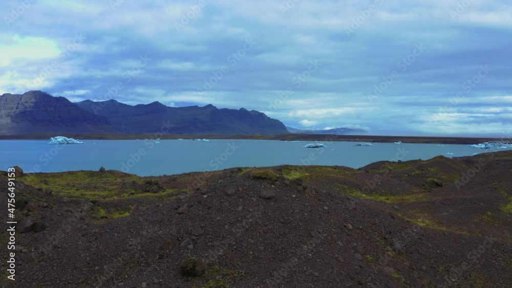 Aerial flight over the rocky hills with great view of Iceland's glaciers in lake