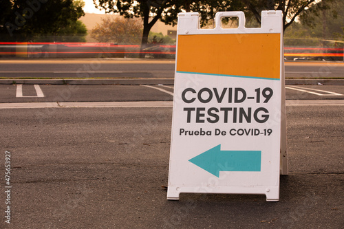 Traffic passes behind a sign for public COVID-19 testing.