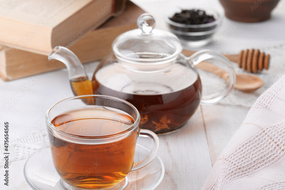 Glass cup of tea and teapot on white wooden table Glass cup of tea and teapot on white wooden table