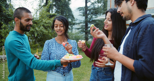 Foto Shallow focus of South Asian friends eating appetizers at an outdoor gathering