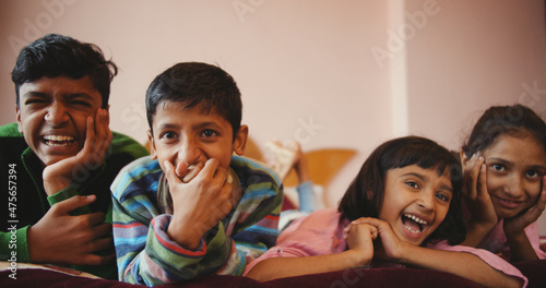 Schilderij op canvas Shallow focus of four siblings enjoying a funny show on the television