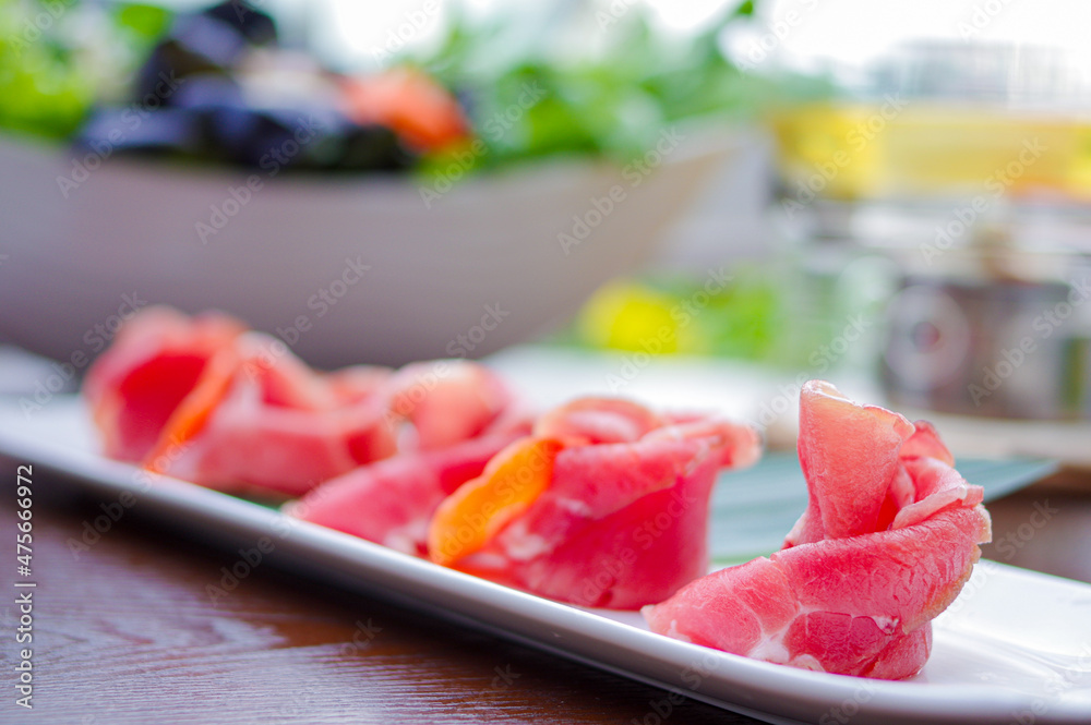 Raw beef mutton rolls for hot pot with carrot and bamboo leaf on white plate