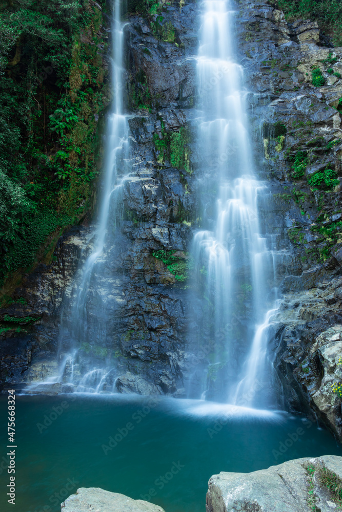 Fototapeta premium waterfall flowing streams falling from mountain with calm blurred water surface long exposure shot
