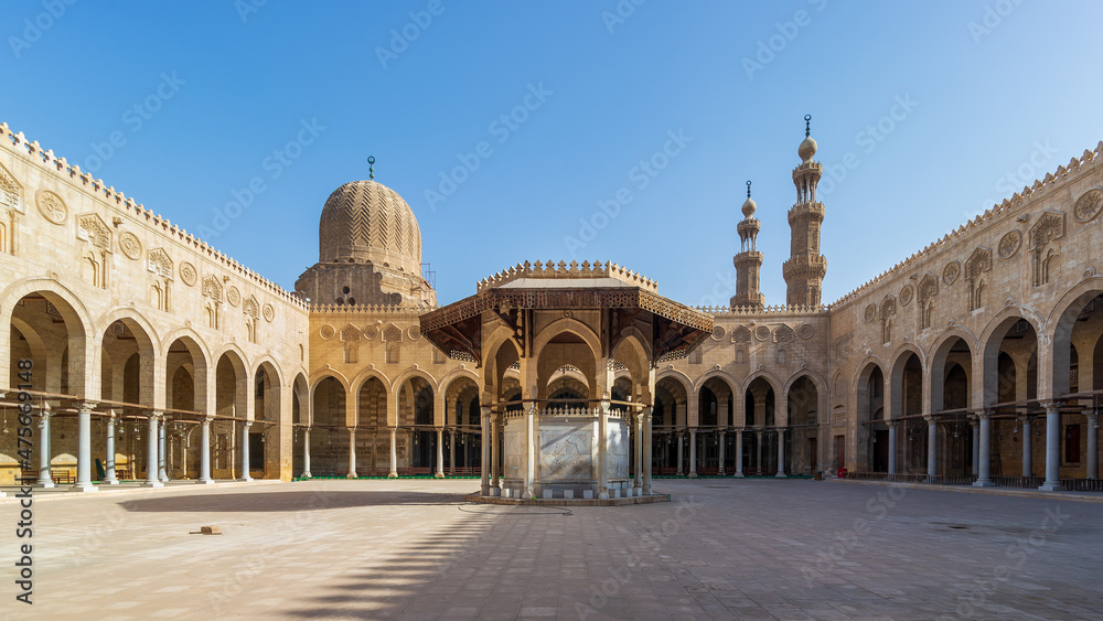 Ablution fountain mediating the courtyard of public historic mosque of Sultan al Muayyad, with background of arched corridors surrounding the courtyard, dome and minarets of the mosque, Cairo, Egypt