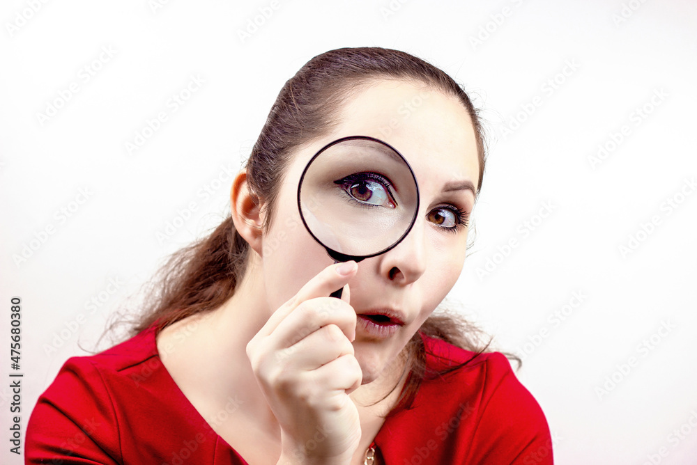 Young attractive woman with magnifying glass in her hand near the eye. Inspection, discovery, research, surprise, curiosity concept Young attractive woman with magnifying glass in her hand near the eye. Inspection, discovery, research, surprise, curiosity concept