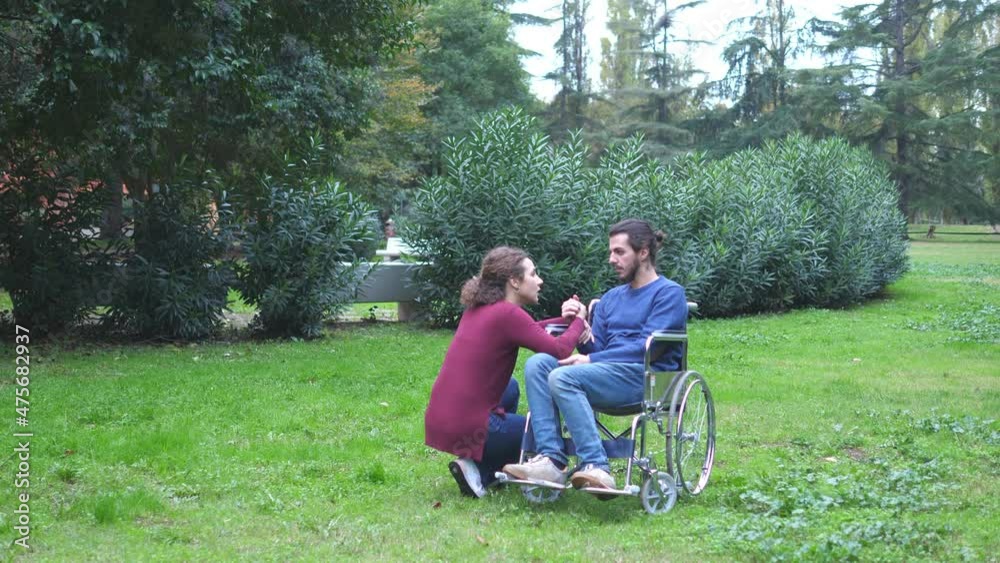 woman kneeling near her boyfriend using wheelchair comforts him woman kneeling near her boyfriend using wheelchair comforts him