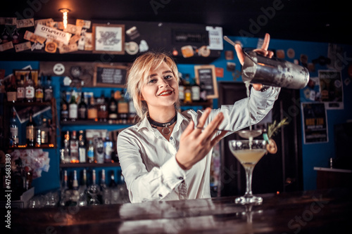 Girl barman creates a cocktail at the alehouse