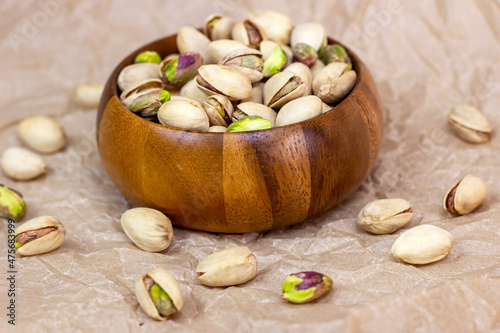 Obraz na plátně Roasted salted pistachio nuts in nutshell in wooden bowl on textured background