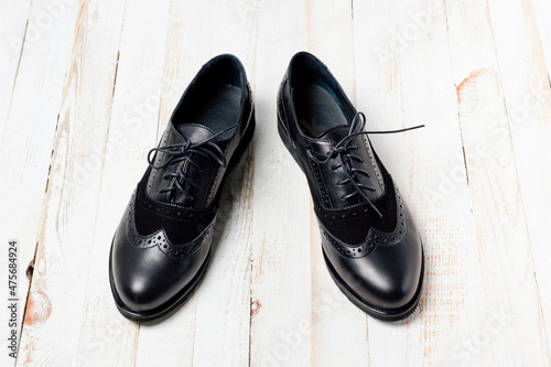 Black imitation leather shoes laced with wide laces. Close-up shot.