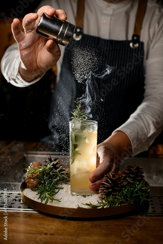 bartender carefully decorates cold alcoholic cocktail with sugar powder photo