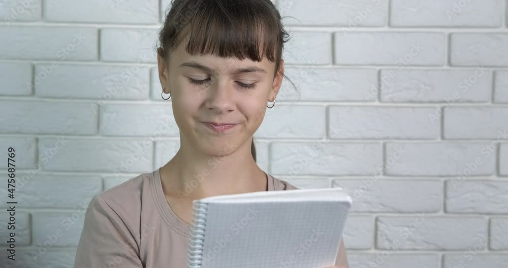 Girl make plan on paper. A little girl make notes in her notebook in her hands. Girl make plan on paper. A little girl make notes in her notebook in her hands.