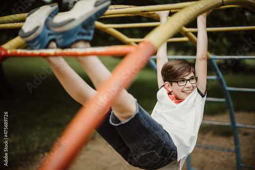 hanging around at climbing frame on playground looking happily to side and enjoy life while being satisfied with this waste of time of simple-minded childhood