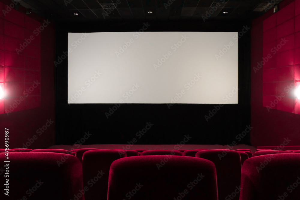 Empty red cinema hall. View of empty white cinema screen with red chairs.