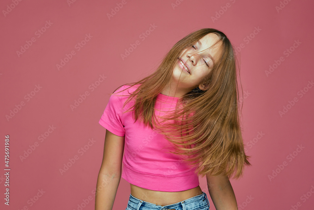 Pretty child girl with long hair shaking head enjoying, having fun with closed eyes on pink studio background Pretty child girl with long hair shaking head enjoying, having fun with closed eyes on pink studio background
