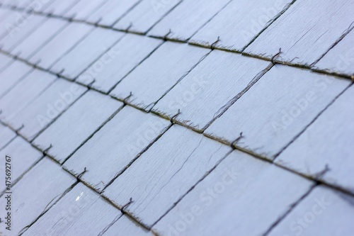 A close up portrait of a blue, black slate tile roof. The long lasting natural shingles are placed in a layered pattern and you can see the hooks keeping them in place.