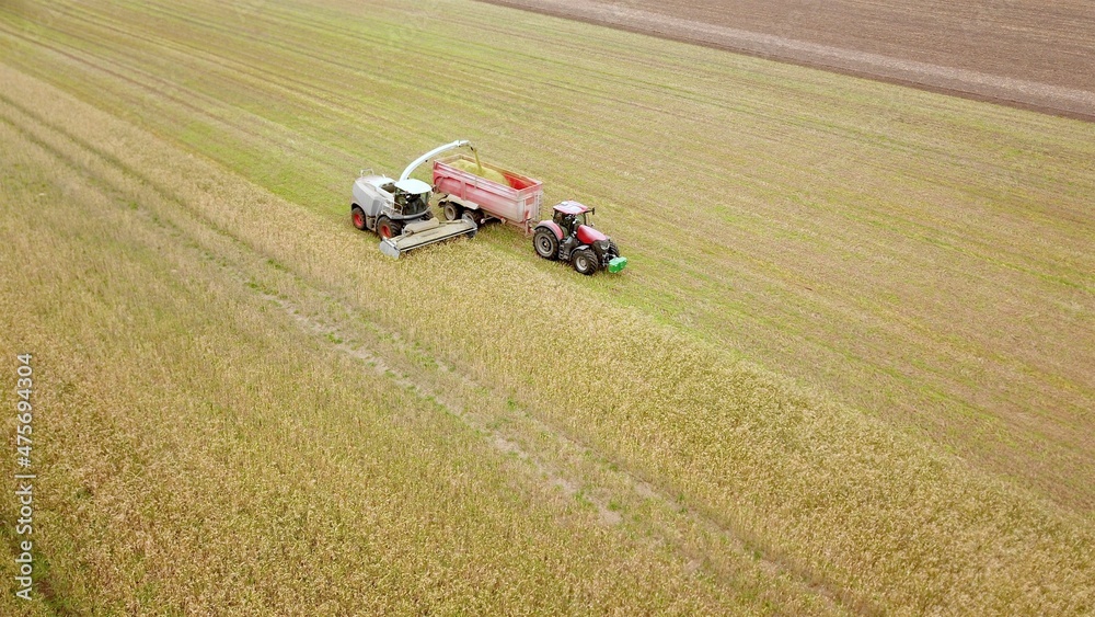 Erntearbeiten aus der Vogelperspektive: Feldhäcksler und Traktor mit Anhänger bei der Ernte auf einem Acker Erntearbeiten aus der Vogelperspektive: Feldhäcksler und Traktor mit Anhänger bei der Ernte auf einem Acker