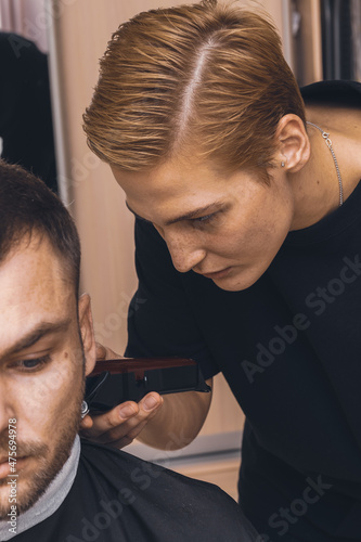 Woman cutting the hair of a man, domestic life.