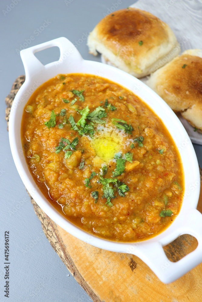 Indian Mumbai Street style Pav Bhaji, garnished with peas, raw onions, coriander and Butter. Spicy thick curry made of out mixed vegetables, served with pav over black background with copy space. Indian Mumbai Street style Pav Bhaji, garnished with peas, raw onions, coriander and Butter. Spicy thick curry made of out mixed vegetables, served with pav over black background with copy space.