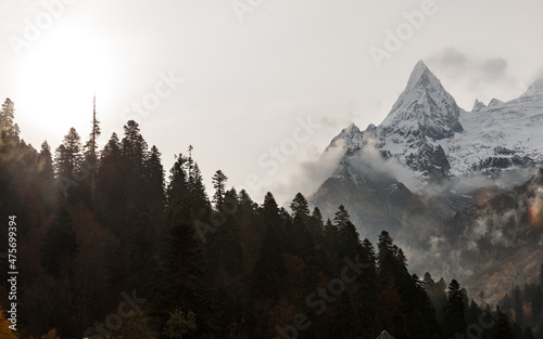 View of Ine Peak, illuminated by the setting sun in the fog against the blue sky, Dombay, Russia. photo