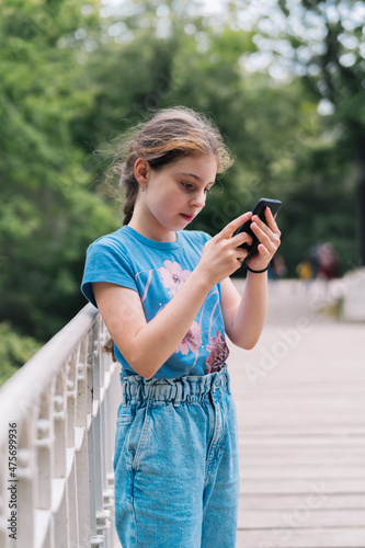 Girl browsing smartphone on bridge in park