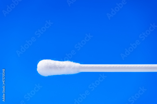 White cotton swab or or cotton bud with copy space against blue background. Coronavirus PCR rapid test for nasopharyngeal swab and detection of SARS-CoV-2.