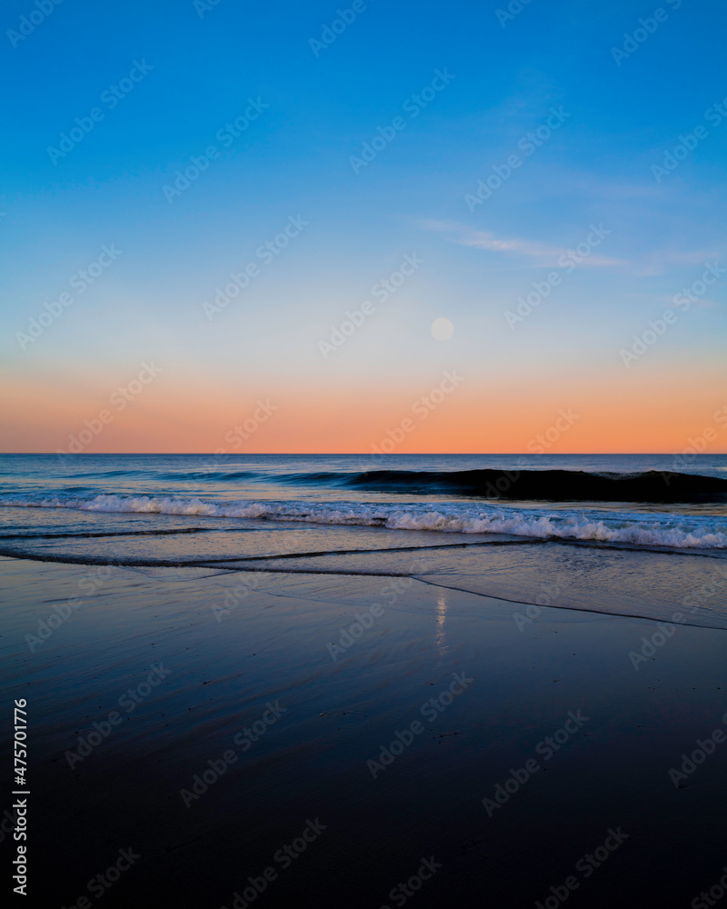 Sunset and moonrise seascape at Cape Cod National Seashore. Pink sunlight over the horizon. Cape Cod National Seashore, created in 1961, is 40 miles long pristine sandy beach, hills, and trails.