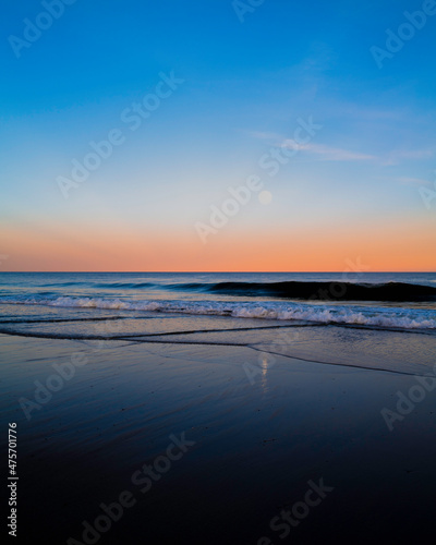Sunset and moonrise seascape at Cape Cod National Seashore. Pink sunlight over the horizon. Cape Cod National Seashore, created in 1961, is 40 miles long pristine sandy beach, hills, and trails.