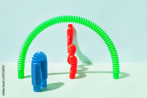 The curved pop tube stands leaning against the wall. Modern still life with antistress toy