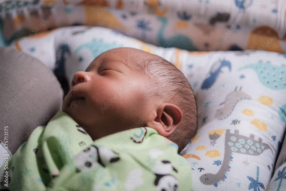 A newborn baby is sleeping comfortably with an adorable expression. Asian child two days old. A newborn baby is sleeping comfortably with an adorable expression. Asian child two days old.