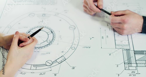 Two engineers work together and use a tablet to search for blueprints and analyze an architectural plan on a table. Agreement by agreement by shaking hands.