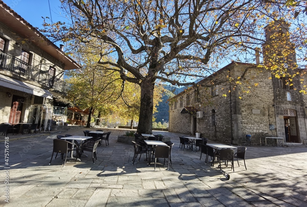 kypseli village central square in autumn season tables chairs plane tree arta perfecture greece