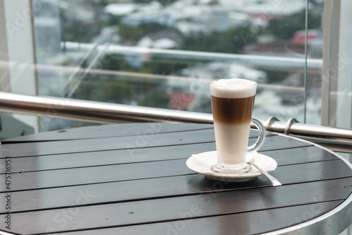 A glass of coffee latte on a table against a blurred background.