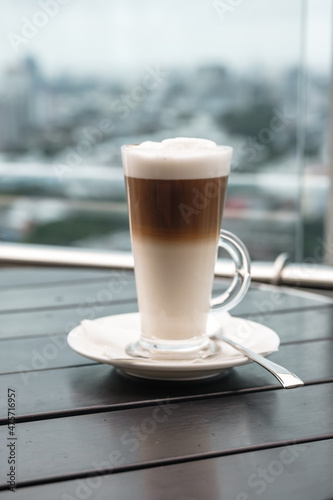 A glass of coffee latte on a table against a blurred background.