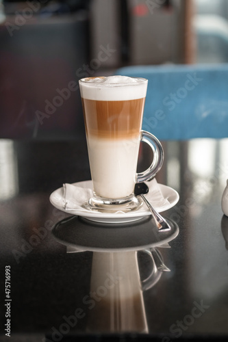 A glass of coffee latte on a table against a blurred background.