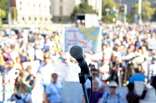 Protest or public demonstration, focus on microphone, blurred crowd of people in the background