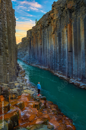 Hiker standing at the bottom of Studlagil Canyon in Iceland at sunset