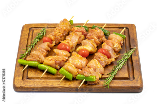 Raw chicken skewers isolated on white background. Close-up of raw chicken skewers marinated in tomato sauce. Horizontal view.