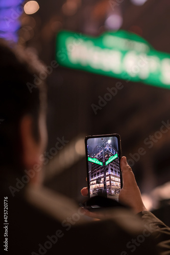 A tourist taking a photo with a smartphone in the city. Mobile photography at night.